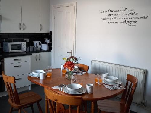 拉德克利夫的住宿－Arise Comfort Home - Dumers Lane, Radcliffe, Bury, Manchester，厨房配有木桌、椅子和桌子