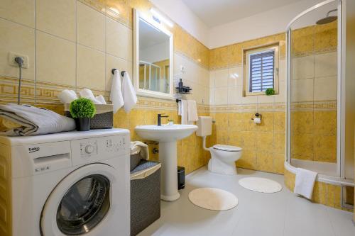 a bathroom with a washing machine and a sink at Nudist friendly villa with fence arround pool and garden to relax and enjoy in Podstrana