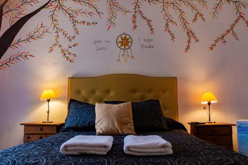 - une chambre avec un lit avec deux lampes et une fresque murale sur les arbres dans l'établissement Hotel San Marcos, à San Marcos Sierras