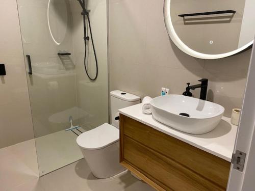 a bathroom with a sink and a toilet and a mirror at Bayona 1 Little Cove in Noosa Heads
