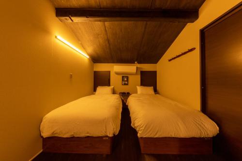 高山市にある静寂 月あかり - 石垣とテラス付露天風呂の和モダン一棟貸宿の黄色の壁の小さな部屋のベッド2台