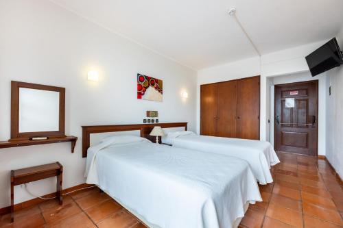 a bedroom with two beds and a mirror and a television at Hotel Residencial Salema in Salema