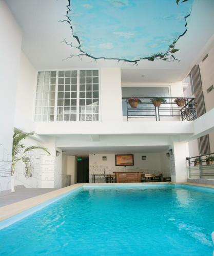 a house with a swimming pool in front of a building at Pavillon Garden Hotel in Nha Trang