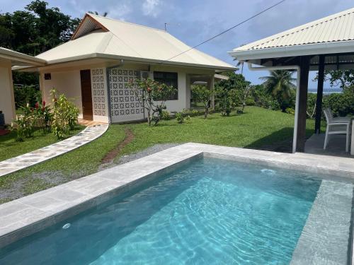 a swimming pool in front of a house at Villa Ura in Uturoa
