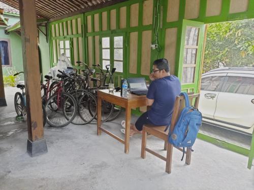 een man aan een tafel met een laptop bij Pendopo Kayuwanan Homestay Syariah in Yogyakarta