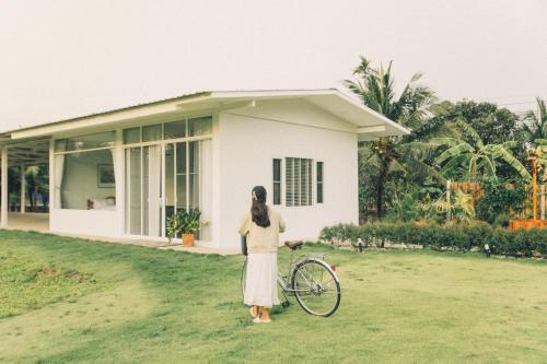 a woman standing in front of a house with a bike at Lukmailhontaiton (ลูกไม้หล่นใต้ต้น) 