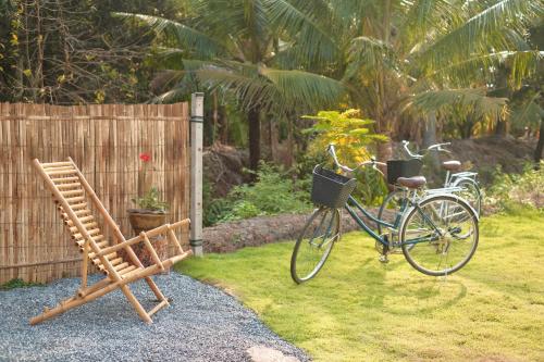 een fiets geparkeerd naast een bank en een hek bij Lukmailhontaiton (ลูกไม้หล่นใต้ต้น) 