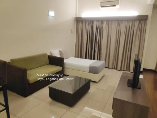uma sala de estar com um sofá, uma cama e uma televisão em M&M Studiostay at Bayou Lagoon Park Resort em Malaca