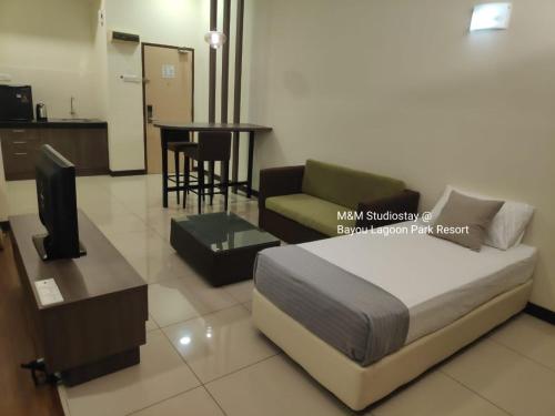 um quarto com uma cama, um sofá e uma mesa em M&M Studiostay at Bayou Lagoon Park Resort em Malaca