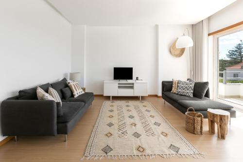 a living room with a black couch and a tv at Terraço da Formosa in Silveira