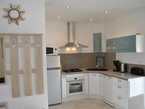 une cuisine avec des armoires blanches et un four à plaques de cuisson dans l'établissement Gîte de charme en Touraine avec clim, jardin et toutes commodités incluses, proche Châteaux de la Loire - FR-1-381-102, à Veigné