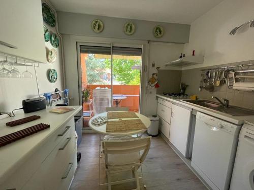 une cuisine avec des armoires blanches et une table à l'intérieur dans l'établissement Arcachon: Appartement T2 avec Accès Direct à la Plage, Terrasse et Parking Privé - FR-1-474-59, à Arcachon