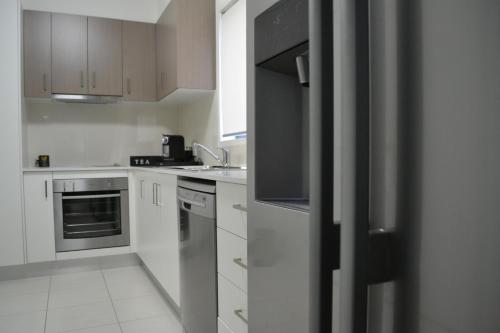 une cuisine avec des armoires blanches et des appareils en acier inoxydable dans l'établissement The Haven Biloela, à Biloela