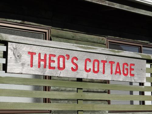 a sign that says theos coffee on the side of a building at Theo's Cottage in Waikanae
