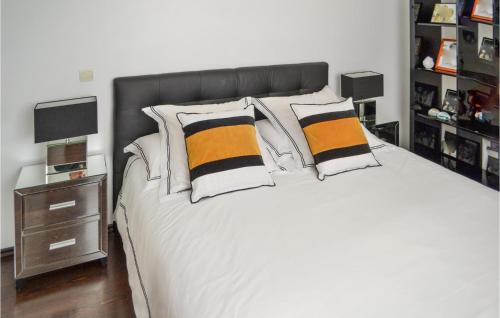 波爾多的住宿－Nice Home In Bordeaux With Outdoor Swimming Pool，一间卧室配有白色的床和黑色和橙色枕头。