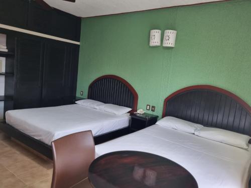 two beds in a room with green walls at Suites Los Arcos in Isla Mujeres