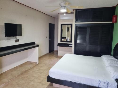 a bedroom with a white bed and a flat screen tv at Suites Los Arcos in Isla Mujeres