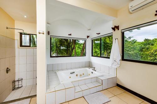 bagno con vasca, doccia e finestre di Flamingo Estates 32 a Playa Flamingo
