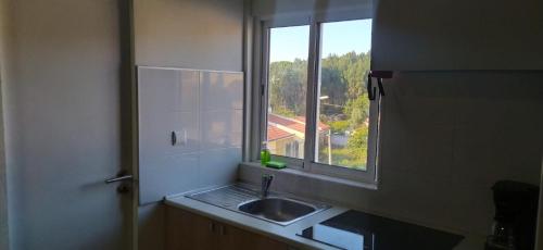 een keuken met een wastafel en een raam bij Ginjals_67 in Almargem