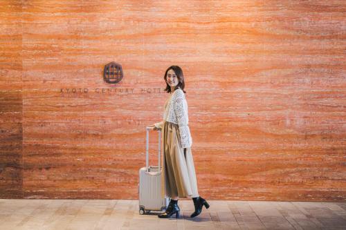 a woman standing next to a wall with a suitcase at Kyoto Century Hotel in Kyoto