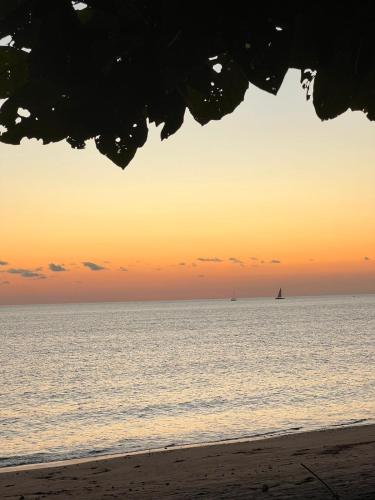 a beach with a sailboat in the ocean at sunset at Suite parentale Villa au bord de la mer chez Saloua in Bouéni
