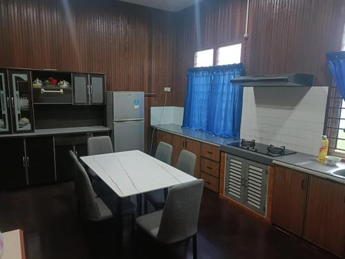 uma cozinha com uma mesa e cadeiras brancas e um fogão em RS HOMESTAY DUNGUN em Kampong Pak Sabah