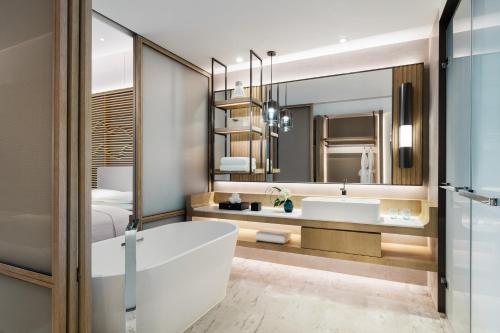 La salle de bains est pourvue d'une baignoire et d'un grand miroir. dans l'établissement Shenzhen Marriott Hotel Golden Bay, à Shenzhen