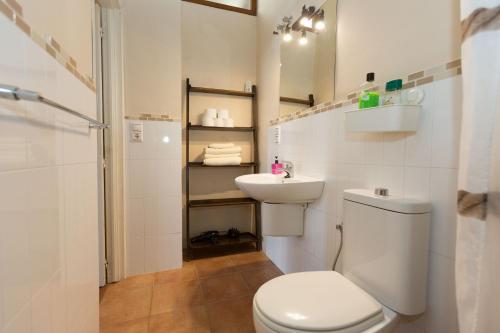 a white bathroom with a toilet and a sink at Apartamentos Deluxe Calle Corredera in Jerez de la Frontera