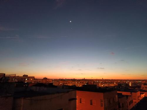 a view of a city at sunset with the moon at CasaCalma in Casablanca