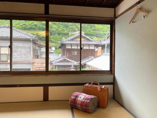 a room with a large window and a suitcase at 跳びしまBASE in Mitarai