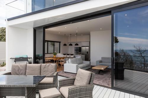 uma sala de estar e de jantar em plano aberto com portas de vidro deslizantes em Oakura Beach Front Apartments em Oakura