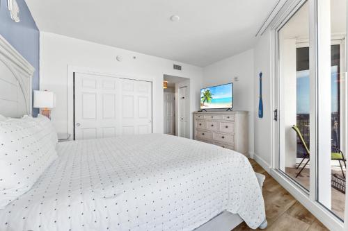9th floor 2BR 2 BATH King Suite Beach shuttle, heated pool! في ديستين: غرفة نوم بيضاء مع سرير أبيض وتلفزيون