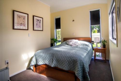 a bedroom with a bed and two windows at The Little House Tutukaka in Tutukaka