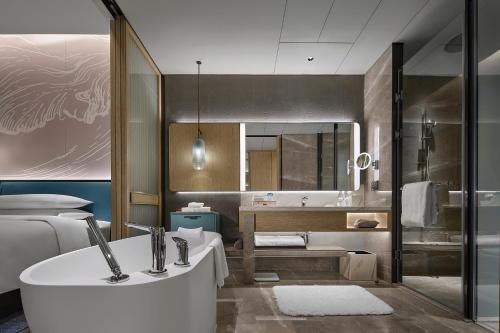 a bathroom with a tub and a toilet and a sink at Qinhuangdao Marriott Resort in Qinhuangdao