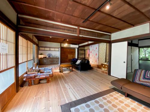 salon z drewnianą podłogą i kanapą w obiekcie 跳びしまBASE w mieście Mitarai