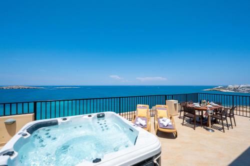 a hot tub on a balcony with a table and chairs at Islet Promenade Seafront Penthouse with breathtaking seaviews and private hot tub on the large terrace by Getawaysmalta in St. Paul's Bay