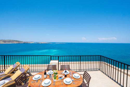 a table on a balcony with a view of the ocean at Islet Promenade Seafront Penthouse with breathtaking seaviews and private hot tub on the large terrace by Getawaysmalta in St. Paul's Bay