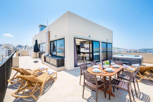a patio with a table and chairs on a balcony at Islet Promenade Seafront Penthouse with breathtaking seaviews and private hot tub on the large terrace by Getawaysmalta in St. Paul's Bay