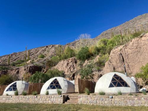 un grupo de tres cúpulas frente a una montaña en Domo La Isla en Tilcara