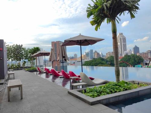 a row of chairs and umbrellas next to a pool at ASTRA at Opus Residences Kuala Lumpur in Kuala Lumpur