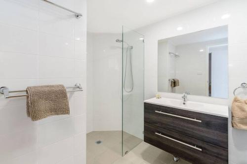 a bathroom with a sink and a glass shower at Pippi Beach Penthouse in Yamba