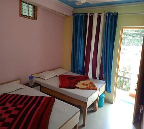 um pequeno quarto com 2 camas e uma janela em Shani Homestay by StayApart em Barkot