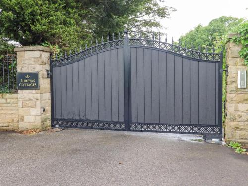 a black gate in a driveway with a stone wall at Sunnyside Shreyas in Wilpshire