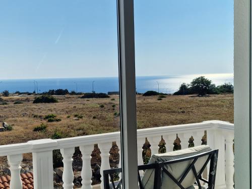 a chair on a balcony looking out at the ocean at Villa Amavi Peyia in Peyia