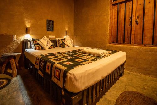 a bedroom with a large bed with a blanket on it at Private Organic House in Udawalawe