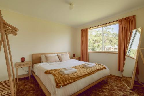 a bedroom with a large bed with two towels on it at Little Belmont in Lunawanna