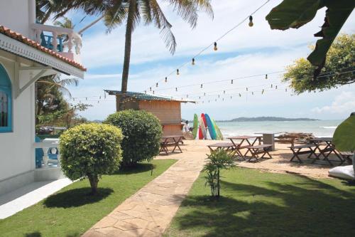 a patio with picnic tables and chairs on the beach at Aquamarine Weligama in Weligama
