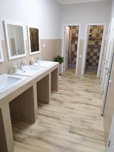 a bathroom with three sinks and two mirrors at Leo in Atyraū