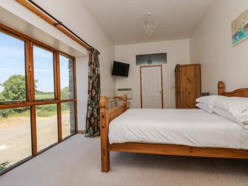 a bedroom with a bed and a large window at The Shippon in Bude