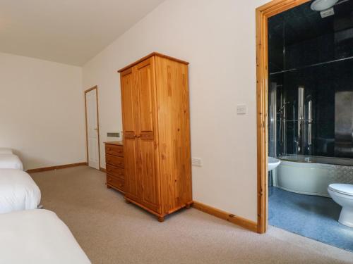 a bedroom with a wooden cabinet next to a bathroom at The Shippon in Bude
